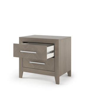 The Child Craft Kieran Nightstand in Crescent Gray features a modern light wood finish, two drawers with sleek metal handles—one partially open—and angled legs for a contemporary look.