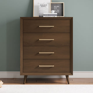 The Child Craft Cranbrook 4 Drawer Chest in Toasted Chestnut features a mid-century modern design with angled legs. Set against a light blue wall, it’s topped with books and a framed print for stylish decor.