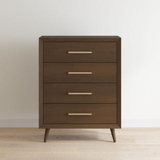 The Child Craft Cranbrook 4 Drawer Chest in Toasted Chestnut features sleek horizontal metal handles and angled legs, offering mid-century modern style. It stands against a plain white wall on a light wood floor.