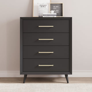 The Child Craft Cranbrook 4 Drawer Chest in Toasted Chestnut features four drawers with sleek metal handles, angled legs, and is styled with framed art and books on top against a light wall on a wooden floor.