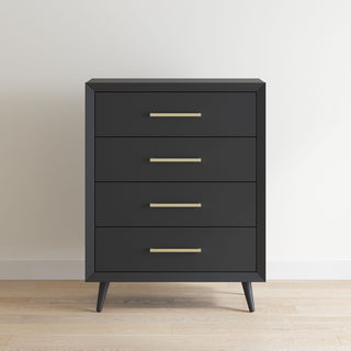 The Child Craft Cranbrook 4-Drawer Chest - Ebony is a modern dresser with gold handles and angled legs, ideal for nurseries or as mid-century decor against a white wall on light wood floors.