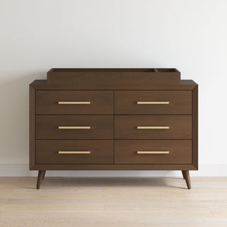 The Child Craft Cranbrook Double Dresser in Toasted Chestnut features six drawers, sleek metal handles, angled legs, and a raised edge—ideal as nursery furniture or to add mid-century modern style to any room.