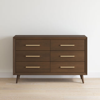 The Child Craft Cranbrook Double Dresser in Toasted Chestnut features six spacious drawers, sleek brass handles, and angled legs—ideal as nursery furniture or a chic mid-century modern piece for any room.