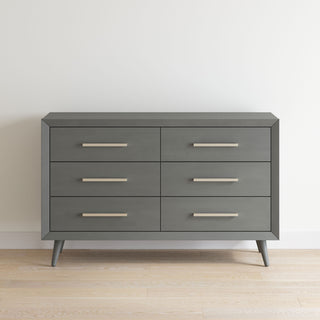 The Child Craft Cranbrook Double Dresser in Lunar Gray features six drawers with sleek silver handles and angled legs, bringing modern mid-century style to any nursery or contemporary bedroom.