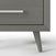 Close-up of the bottom corner of the Child Craft Cranbrook Nightstand in Lunar Gray, featuring a silver horizontal handle and an angled tapered leg.