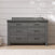 The Child Craft Denman 6-Drawer Dresser in Midnight Grey stands against a white shiplap wall with a sink on top, light and shadows on the wall, and a rug placed in front.