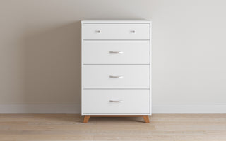 The Child Craft Soho 4 Drawer Chest in White/Natural features a minimalist, modern design with simple handles and short wooden legs, standing out against light walls and wood floors.