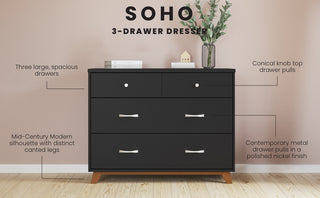 The Child Craft Soho 3-Drawer Dresser in Ebony features three spacious drawers with metal pulls, canted legs, and conical knobs. Shown against a blush pink wall with decor and a plant on top.
