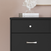A Child Craft Soho 3-Drawer Dresser in Ebony stands against a light pink wall, topped with two stacked books and a white decorative coral sculpture.
