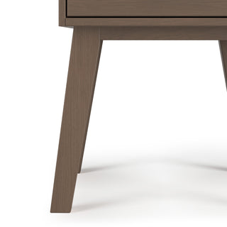 Close-up of the lower half of the Child Craft Soho Nightstand in Dusty Heather, featuring angled legs and a drawer—ideal for nursery furniture—set against a white background.
