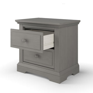 The Child Craft Jordyn Nightstand in Lunar Gray features a classic design with crown molding, two drawers—one partially open—and smooth edges. Ready-to-assemble and baby-safe, it’s a sturdy choice for any bedroom.