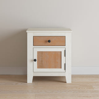 The Child Craft Ocean Grove Nightstand, White/Brown, features a compact design with a drawer and cabinet door accented by natural wood panels and black knobs—ideal for adding a nautical farmhouse style to your nursery.