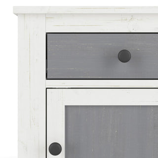 Close-up of the Child Craft Ocean Grove Nightstand in White/Gray, featuring a distressed, rustic finish with a drawer and cabinet door, each adorned with a round black knob.