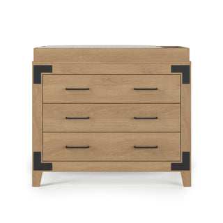 The Child Craft Lucas Dresser in Nutmeg features three drawers with black metal handles, black corner brackets, and four short legs. Its top has a raised edge, making it suitable for use as a changing table.