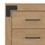 Close-up of the Lucas Dresser by Child Craft in Nutmeg finish, showing two drawers with black horizontal handles and a black metal corner bracket attached to the top left corner.