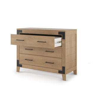 The Child Craft Lucas Dresser in Nutmeg features three drawers, black metal corner accents, and long black handles. The top drawer is open to display neatly folded white bedding inside.