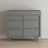 A modern gray Child Craft dresser with three geometric-patterned drawers stands on tapered legs, ideal for pairing with the F01792 - Universal Changing Table Topper in Lunar Gray against a white wall and light wood floor.