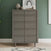 The Child Craft Surrey Hill 5 Drawer Chest in Lunar Gray stands against a green wall, topped with vases and framed artwork. A patterned rug is partially visible on the floor.