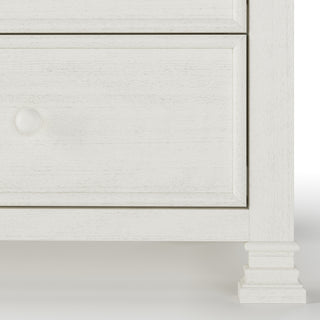 Close-up of the lower section of the Child Craft Westgate Double Dresser in Vintage Linen, featuring part of two drawers with round knobs and a decorative leg on the bottom right.
