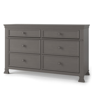 The Child Craft Westgate Double Dresser in Chelsea Gray features six drawers with round knobs, decorative molding, and four short squared legs—ideal as a stylish nursery dresser.