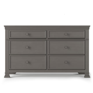 The Child Craft Westgate Double Dresser in Chelsea Gray offers six spacious drawers, round knobs, and decorative trim. Made from pine, it’s a stylish storage solution perfect for any nursery.