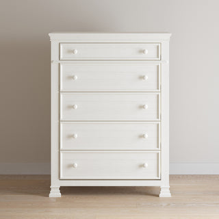 The Child Craft Westgate 5-Drawer Chest in Vintage Linen features a simple, classic design with round knobs, and stands against a beige wall on a light wood floor.