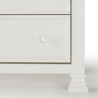 Close-up of the lower right corner of the Child Craft Westgate 5-Drawer Chest in Vintage Linen, featuring a round knob, two drawer fronts, and decorative square legs.