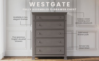 The Child Craft Westgate 5-Drawer Chest in Chelsea Gray stands by a white paneled wall, featuring two finishes, crown molding, solid wood pulls, English dovetail drawers, and arrives fully assembled.