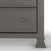 Close-up of the lower section of the Child Craft Westgate 5-Drawer Chest in Chelsea Gray, featuring one drawer with a round knob, decorative moldings, and part of its carved leg against a white background.