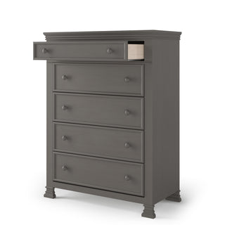 The Child Craft Westgate 5-Drawer Chest in Chelsea Gray is a tall wooden dresser featuring five drawers—one partially open to reveal the empty interior—simple round knobs, and stands on short decorative legs.