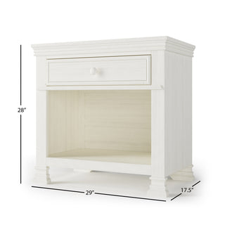 The Child Craft Westgate Nightstand in Vintage Linen is a white wood nightstand with one drawer and open shelf, perfect for a nursery. It measures 28" H x 29" W x 17.5" D.