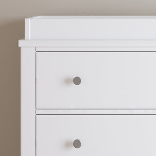 The Child Craft Harmony 3-Drawer Dresser with Changing Table Topper in matte white features clean lines and silver knobs, making it a stylish, practical nursery storage solution for any room.