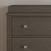 A close-up of the upper left corner of the Child Craft Harmony 3-Drawer Dresser with Changing Table Topper in Dapper Gray, featuring two drawers with round silver knobs, set against a plain light-colored wall.