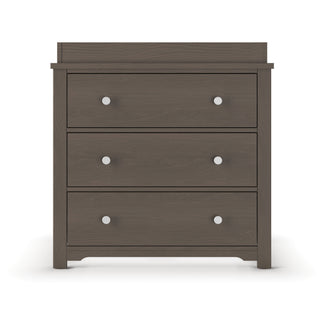 The Child Craft Harmony 3-Drawer Dresser with Changing Table Topper in Dapper Gray features three drawers with two round silver knobs each, shown against a white background.