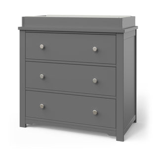 The Child Craft Harmony 3-Drawer Dresser with Changing Table Topper in Cool Gray features three drawers with round silver knobs and a raised-edge top, making it perfect nursery furniture or for use as a changing table.