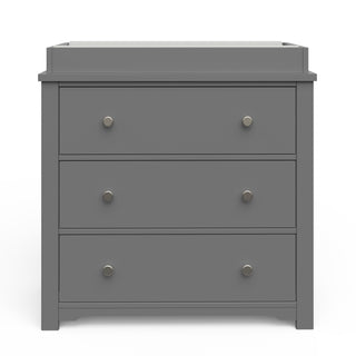 The Child Craft Harmony 3-Drawer Dresser with Changing Table Topper in Cool Gray features silver knobs and three drawers, making it ideal nursery furniture. It's shown set against a white background.