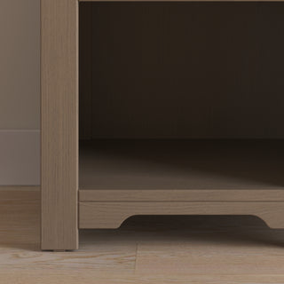 A close-up of the lower section of the Child Craft Harmony Nightstand in Dusty Heather, featuring child-safe finishes and an empty shelf for practical bedside storage, standing on a light wood floor against a beige wall.