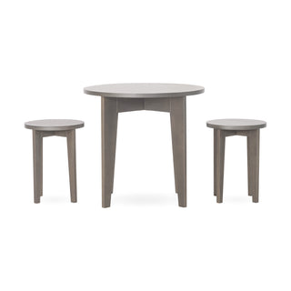 The Child Craft Geo Table and Stools Set in Dapper Gray features a round wooden table with three legs, paired with two matching round three-legged stools, all in a light grayish-brown finish against a plain white background.