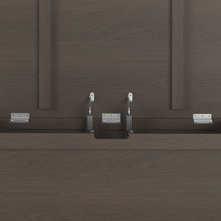 Close-up of the Child Craft Harmony 33" Kids Toy Box in Dapper Gray, showing its dark wood panels and metal brackets and hinges used for assembly. Vertical and horizontal wood panels feature in the background.