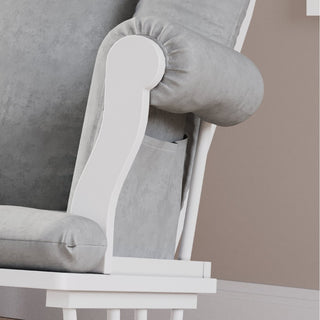 Close-up of the Child Craft Cozy Glider and Ottoman in Matte White, featuring light gray cushions, rolled armrest with side pocket, white wooden supports, and partial seat view against a beige wall.
