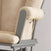 A close-up of the Child Craft Tranquil Nursery Glider Cushion in beige, featuring a wooden armrest and a handy side fabric pocket, set against a light background.