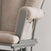 Close-up of the Child Craft Tranquil Nursery Glider Cushion, a beige, cushioned chair with a wooden frame. It features a built-in side pocket and plush seat and backrest—ideal for relaxing with your baby.