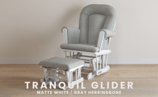 A matte white Child Craft Tranquil Nursery Glider and Ottoman with gray herringbone upholstery sits on a light wood floor against a beige wall. Text reads: TRANQUIL NURSERY GLIDER AND OTTOMAN, MATTE WHITE / GRAY HERRINGBONE.