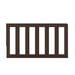 The Child Craft F09501 Toddler Guard Rail in Brushed Truffle features vertical slats and attaches to beds or cribs as part of a crib conversion to help prevent falls.