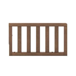 The Child Craft F09501 Toddler Guard Rail in Cocoa Bean features five vertical slats with a solid top and bottom frame, designed for easy crib conversion, shown against a white background.