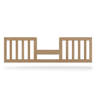 The Child Craft F09514 Toddler Guard Rail in Nutmeg features vertical slats and a central gap for easy access, providing safety and fall prevention when converting your crib to a toddler bed.
