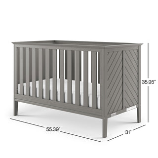 The Child Craft Atwood 3-in-1 Euro Convertible Crib in Lunar Gray features vertical slats, chevron-patterned end panels, and includes a mattress. Dimensions: 55.39"L x 31"W x 35.95"H.