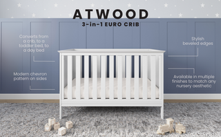 The Child Craft Atwood 3-in-1 Euro Convertible Crib in Matte White features vertical slats and beveled edges, set on a gray rug with a star-patterned blue wall. This modern crib offers multiple finishes and converts to grow with your child.