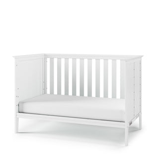 The Child Craft Atwood 3-in-1 Euro Convertible Crib in Matte White features a simple, modern design with vertical slats, a solid headboard, and includes a white mattress for your toddler's comfort.