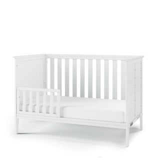 The Child Craft F09501 Toddler Guard Rail in matte white features sturdy wood construction, open side and back slats, a safety guard rail, and a sleek modern design for your toddler's bed.